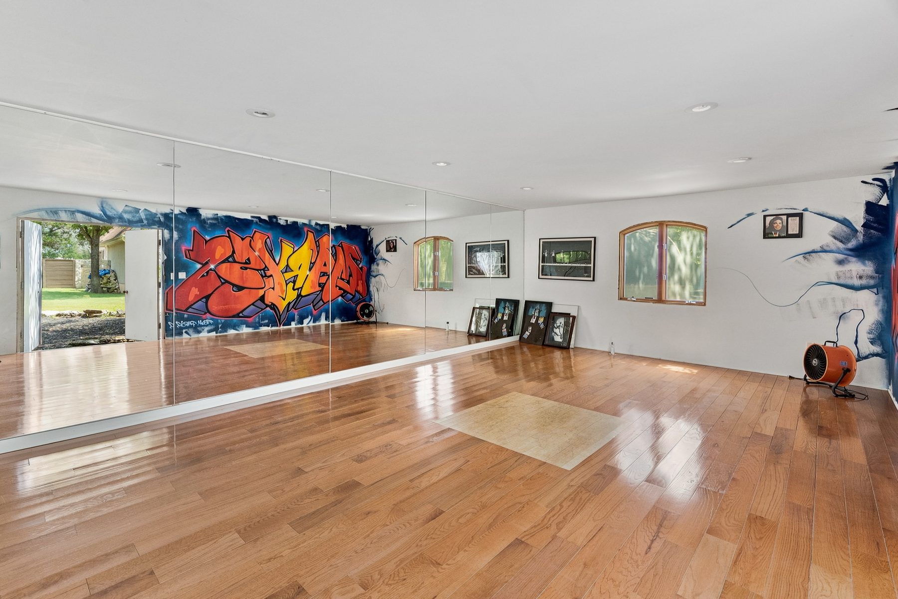 Dance studio with wall-to-wall mirrors, hardwood floor and graffiti mural