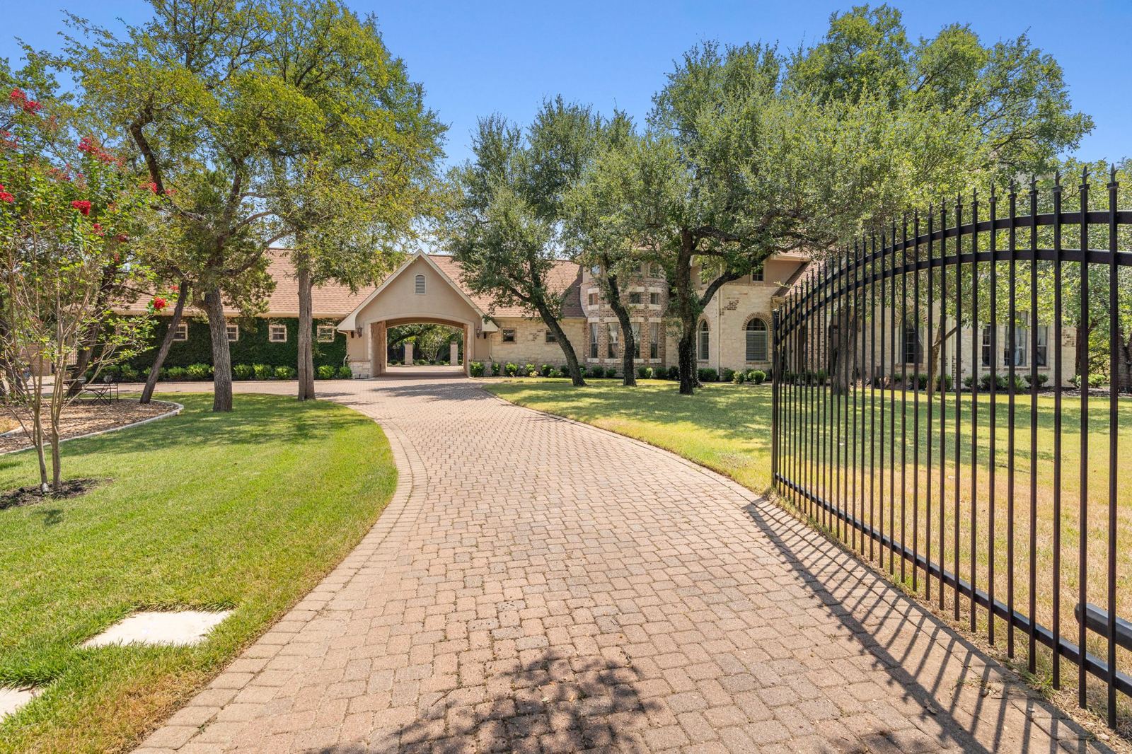 Paver drive lined with iron fence and oaks