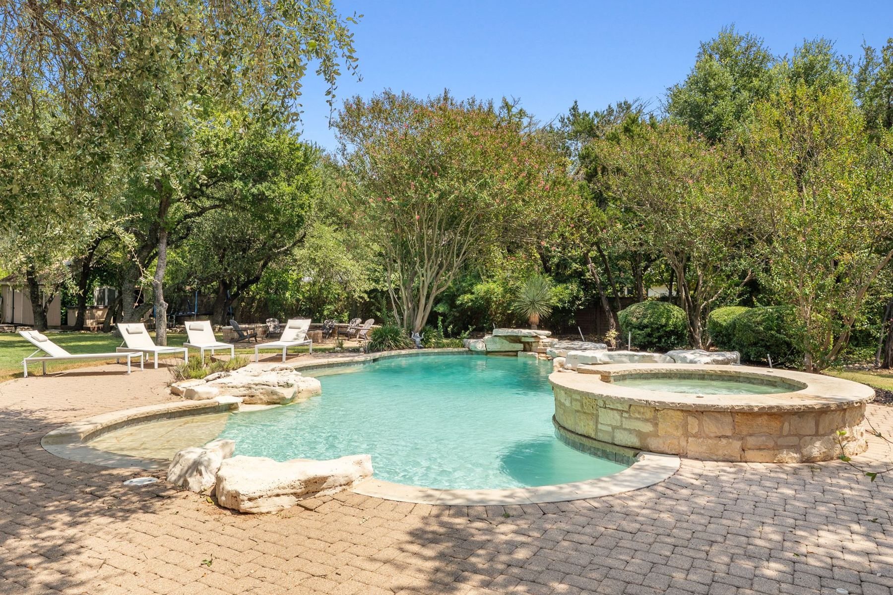 Free-form pool with raised spa among mature trees