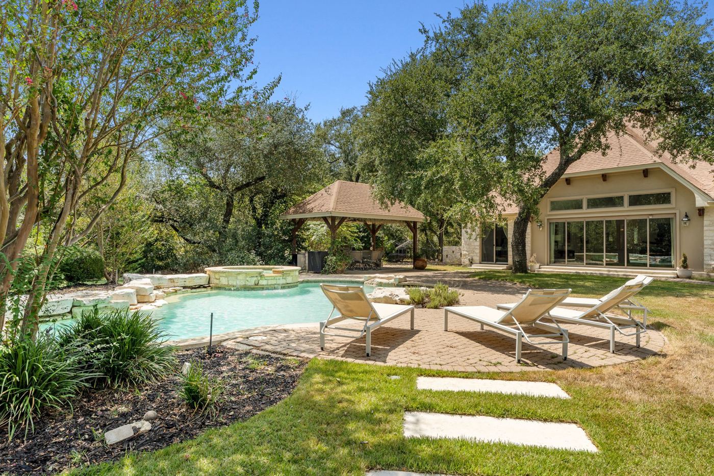 Pool loungers beneath the oaks