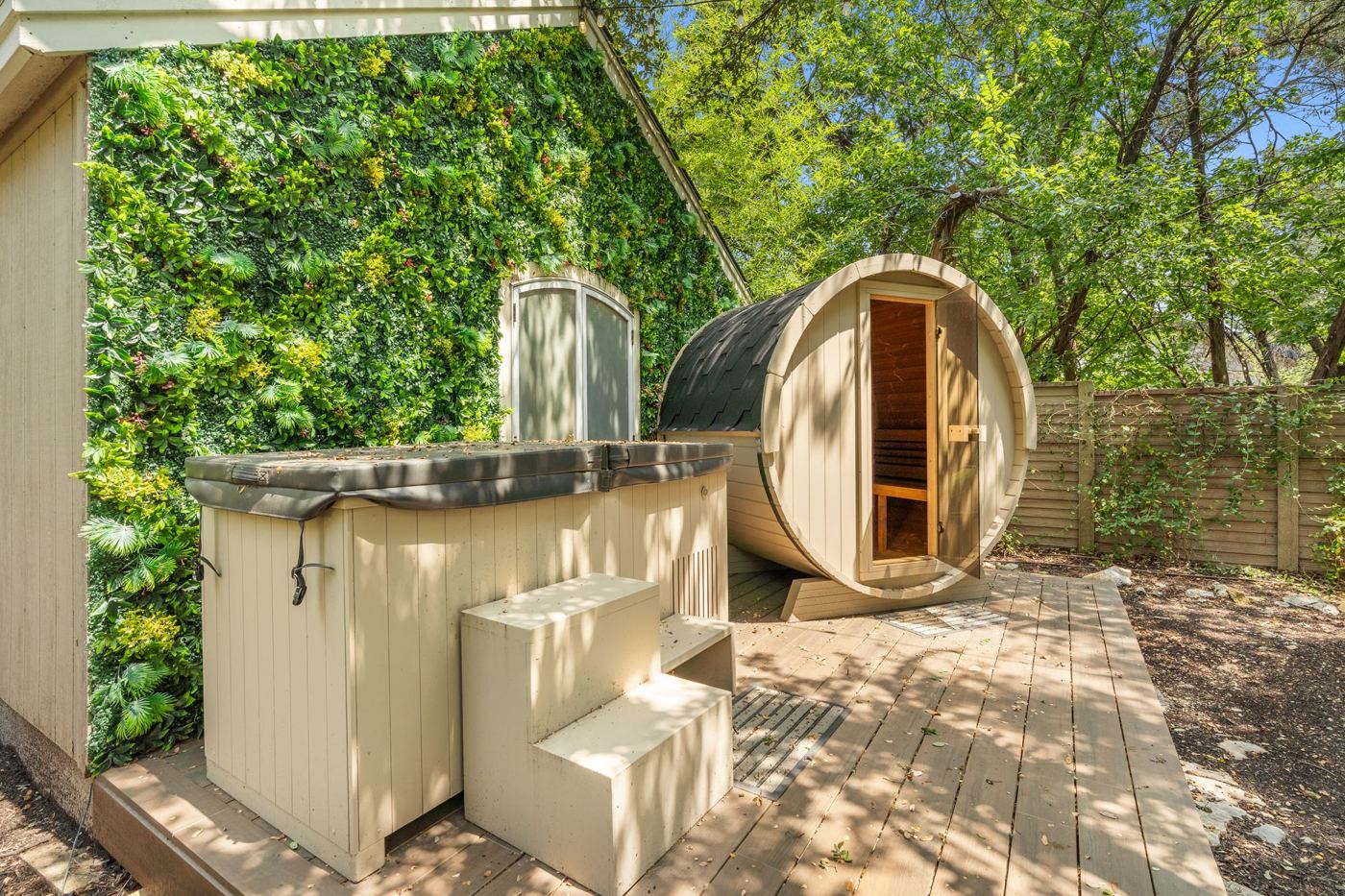 Barrel sauna and plunge tub before a living green wall