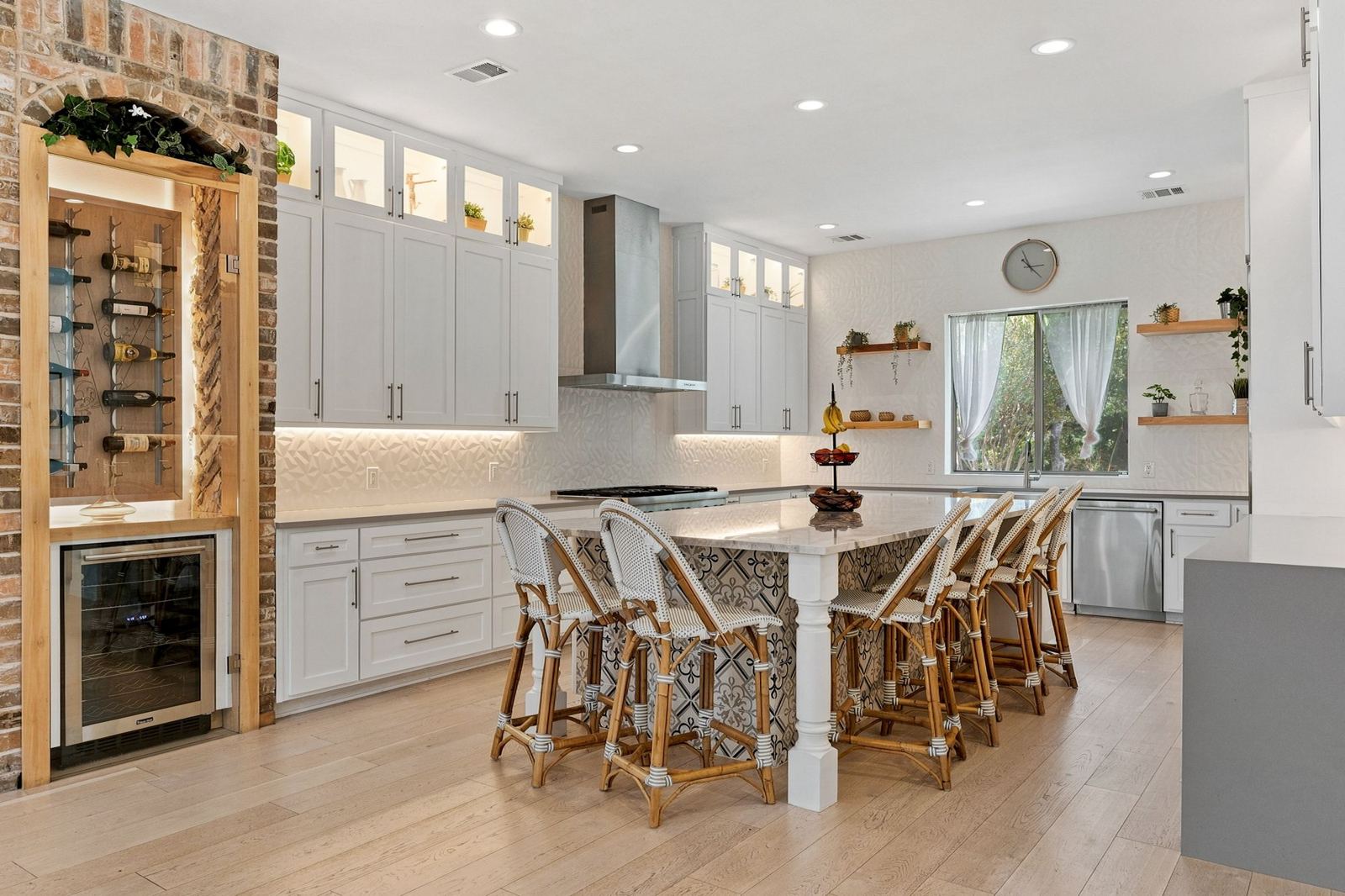 White chef’s kitchen with island seating and wine wall
