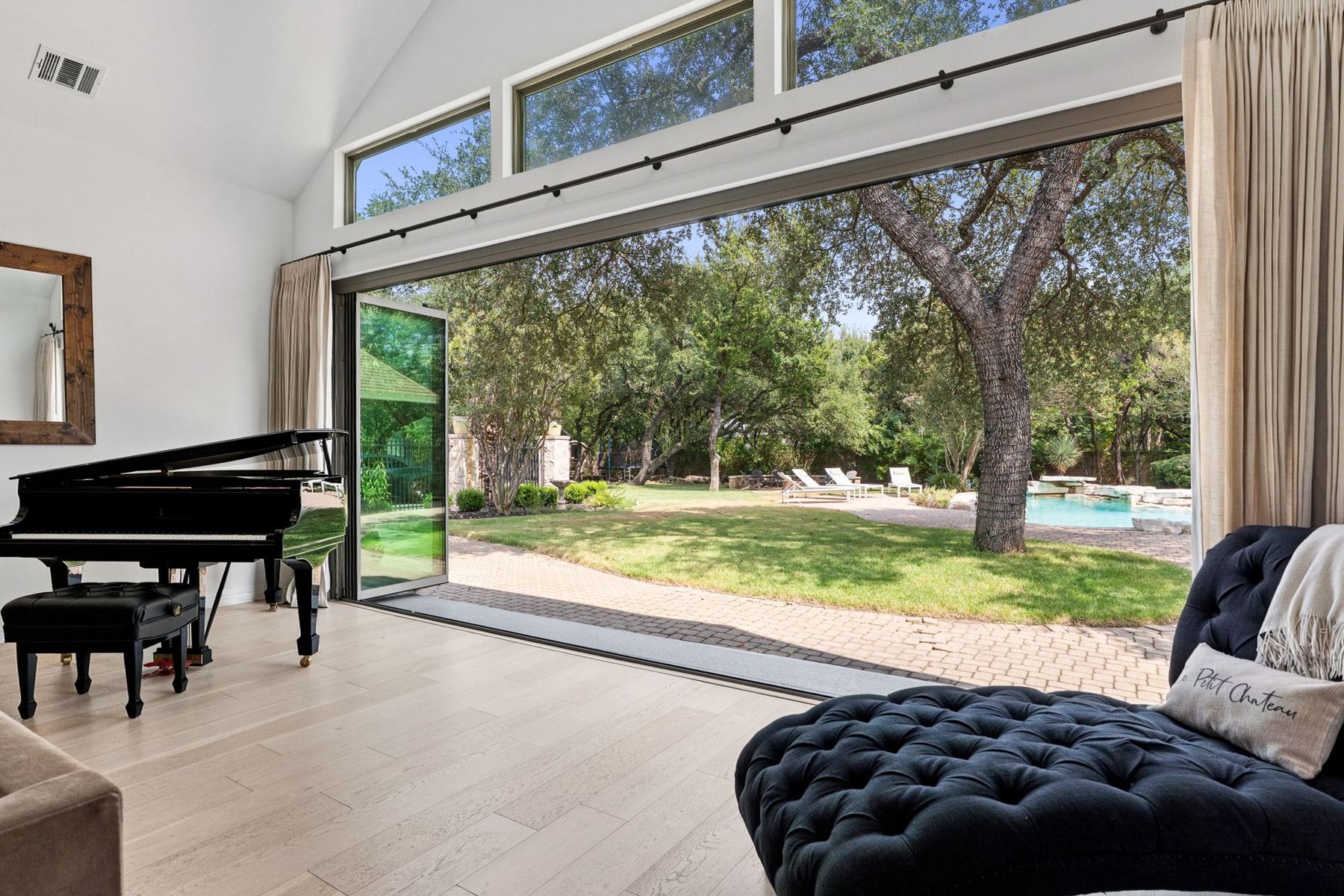 Great room with grand piano and folding glass wall open to the pool